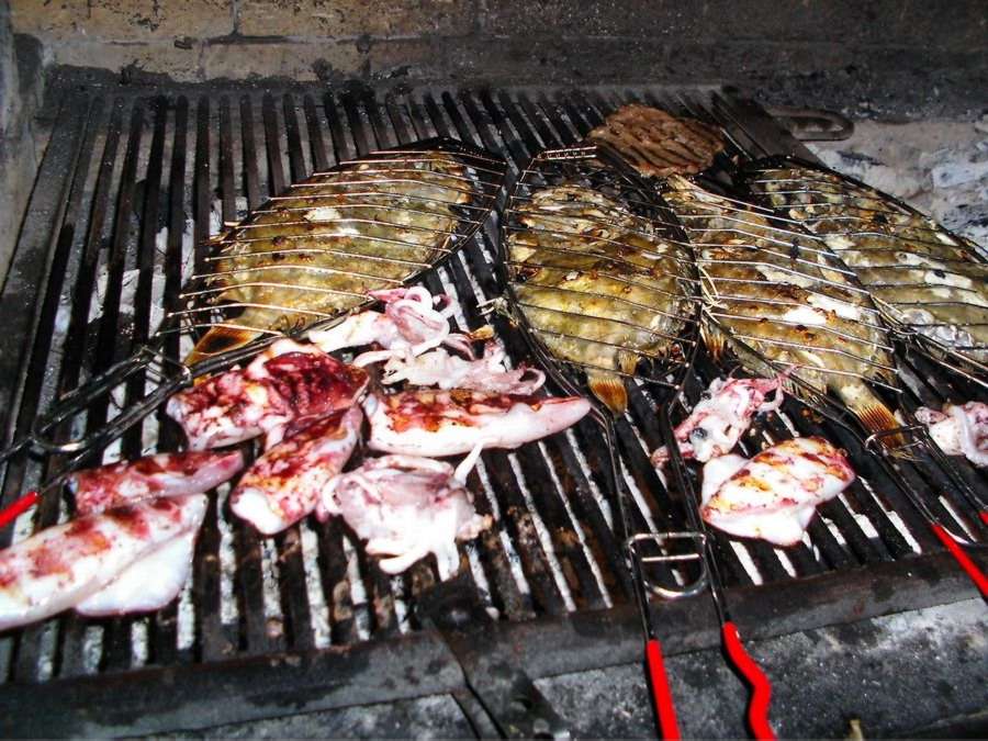 Fisch, Calamari und Fleisch: auf dem grossen Holzkohlengrill frisch für Sie zubereitet. Fish, calamari and meat: always  prepared freshly on the large barbecue.